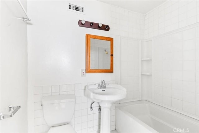 bathroom featuring bathtub / shower combination, toilet, and tile walls