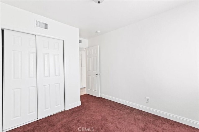 unfurnished bedroom featuring a closet and dark colored carpet