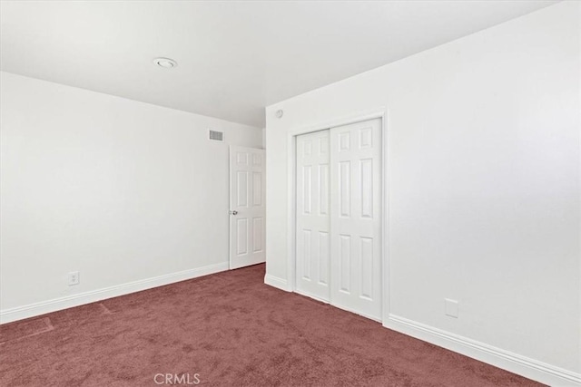 unfurnished bedroom with a closet and dark carpet