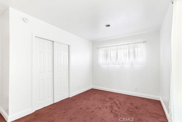 unfurnished bedroom featuring dark colored carpet and a closet