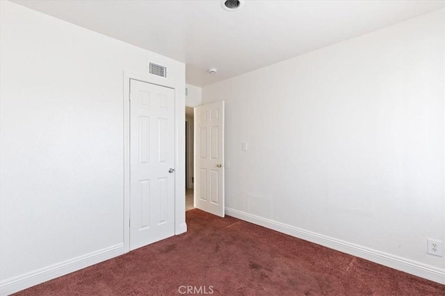 unfurnished room featuring dark colored carpet