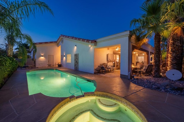 pool at night with an in ground hot tub and a patio