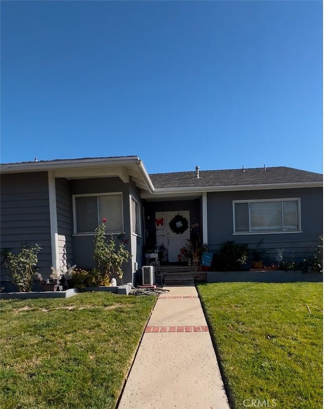 ranch-style house with central AC unit and a front lawn