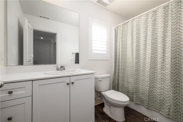 bathroom with hardwood / wood-style floors, vanity, toilet, and walk in shower