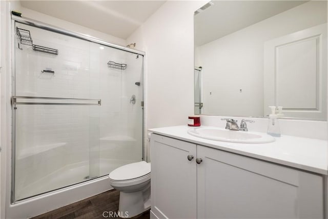 bathroom with an enclosed shower, vanity, toilet, and wood-type flooring