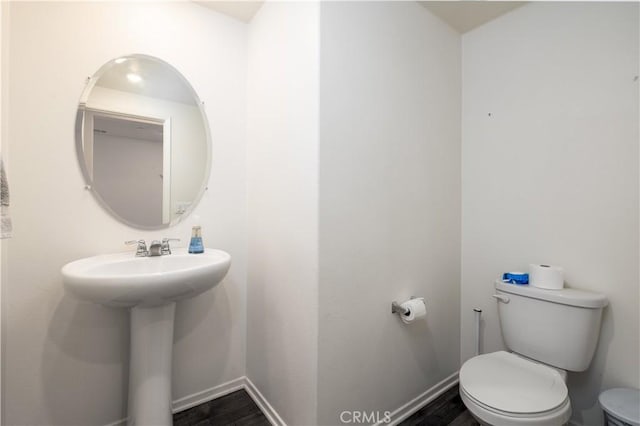 bathroom with wood-type flooring, toilet, and sink