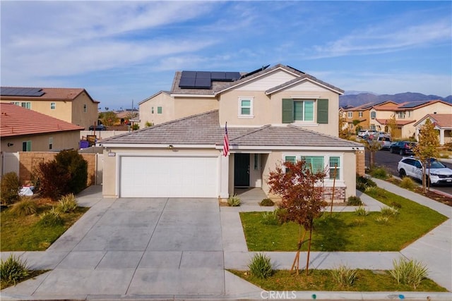 view of front property with a mountain view, solar panels, a garage, and a front lawn