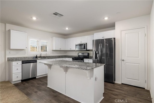 kitchen with white cabinetry, a center island, sink, dark hardwood / wood-style flooring, and appliances with stainless steel finishes