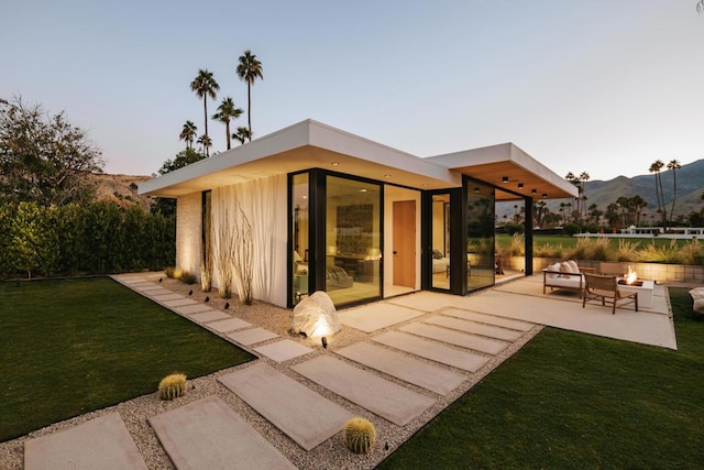 back of house with a mountain view, a yard, a patio, and a fire pit