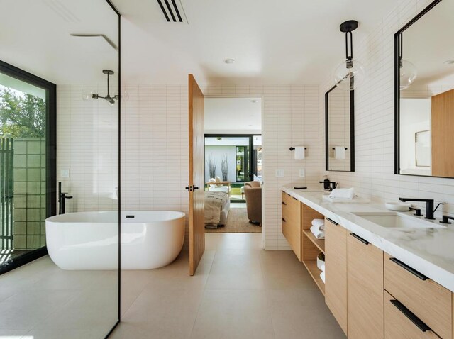 bathroom featuring a tub, tile walls, vanity, and tile patterned flooring