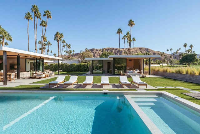 view of pool featuring an outdoor living space, a patio area, a mountain view, and a yard