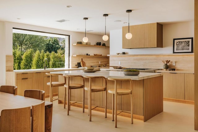 kitchen with decorative light fixtures, sink, a breakfast bar, and a kitchen island