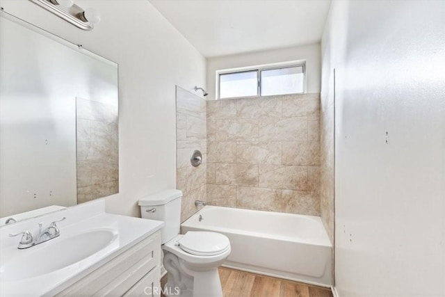 full bathroom featuring hardwood / wood-style floors, tiled shower / bath combo, toilet, and vanity