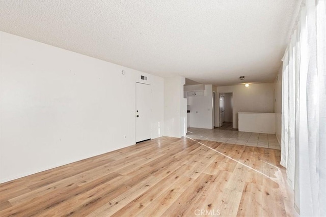 unfurnished living room featuring a textured ceiling and light hardwood / wood-style floors