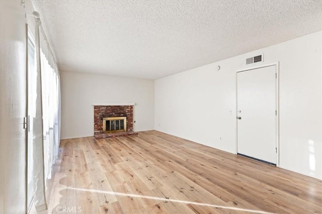 unfurnished living room with a textured ceiling, a fireplace, and light hardwood / wood-style flooring