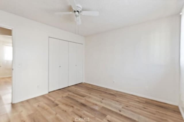 unfurnished bedroom with ceiling fan, a closet, and light hardwood / wood-style floors