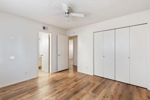 unfurnished bedroom with ensuite bathroom, light hardwood / wood-style flooring, ceiling fan, a textured ceiling, and a closet