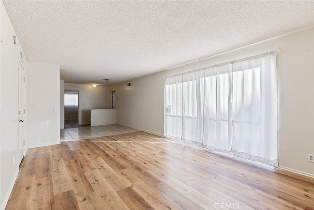 empty room with light hardwood / wood-style floors and a textured ceiling