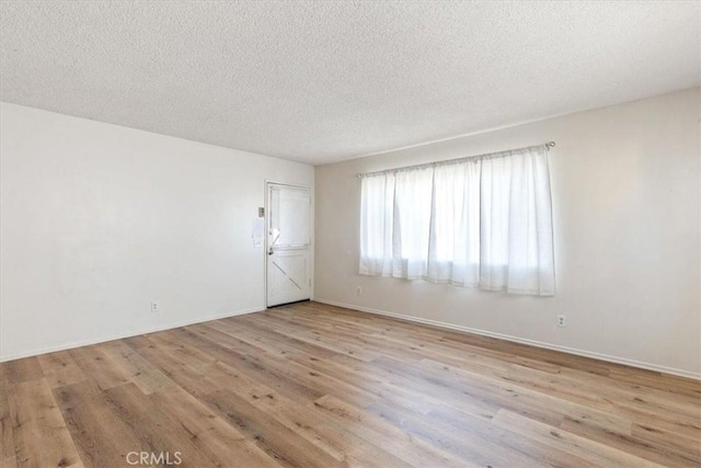 empty room with light hardwood / wood-style floors and a textured ceiling