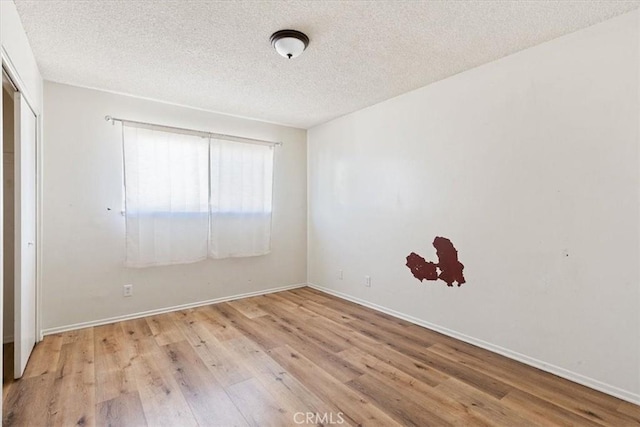 unfurnished room featuring light wood-type flooring and a textured ceiling