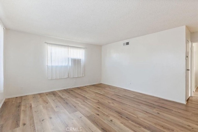 empty room featuring a textured ceiling and light wood-type flooring