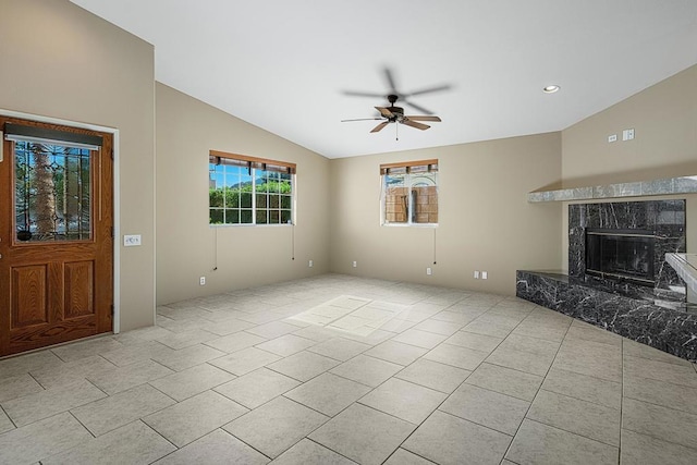 unfurnished living room with ceiling fan, a premium fireplace, light tile patterned floors, and vaulted ceiling