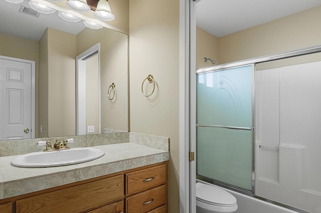 full bathroom featuring shower / bath combination with glass door, vanity, and toilet