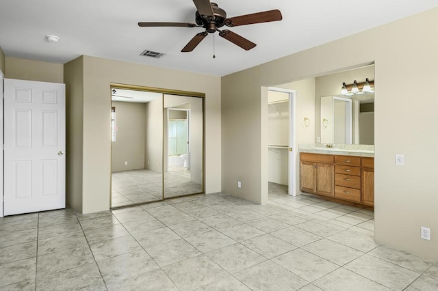 unfurnished bedroom featuring ceiling fan, light tile patterned floors, sink, and ensuite bath