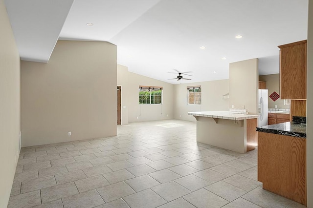 interior space with kitchen peninsula, a kitchen breakfast bar, ceiling fan, white fridge with ice dispenser, and lofted ceiling