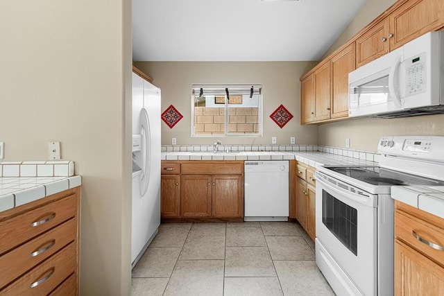 kitchen featuring tile counters, white appliances, sink, and light tile patterned floors