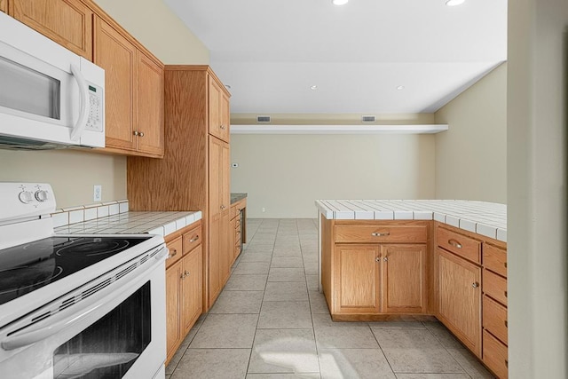 kitchen featuring kitchen peninsula, light tile patterned floors, white appliances, and tile counters