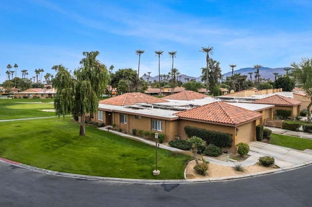 mediterranean / spanish house featuring a mountain view, a garage, and a front lawn