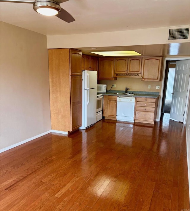 kitchen featuring white appliances, dark wood-type flooring, and sink