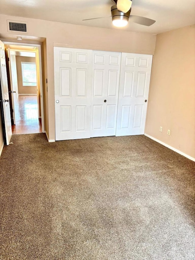 unfurnished bedroom featuring ceiling fan, a closet, and dark carpet