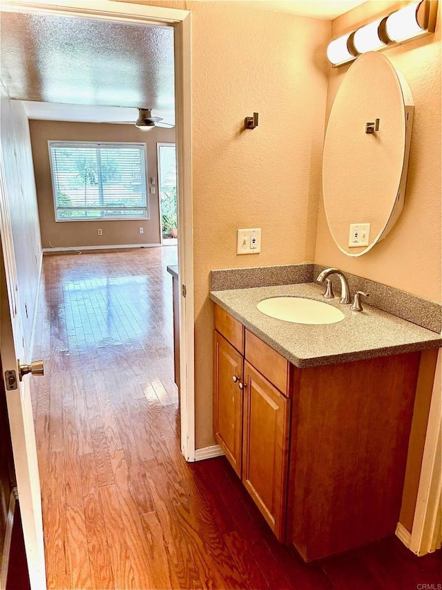 bathroom with vanity, hardwood / wood-style floors, a textured ceiling, and ceiling fan