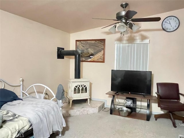 bedroom with carpet flooring, ceiling fan, a wood stove, and vaulted ceiling