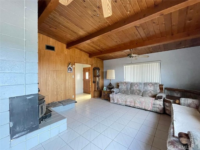 tiled living room with a wood stove, wooden walls, vaulted ceiling with beams, ceiling fan, and wood ceiling