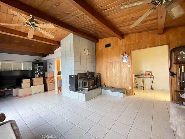 tiled living room featuring a wood stove, ceiling fan, lofted ceiling with beams, wood walls, and wood ceiling