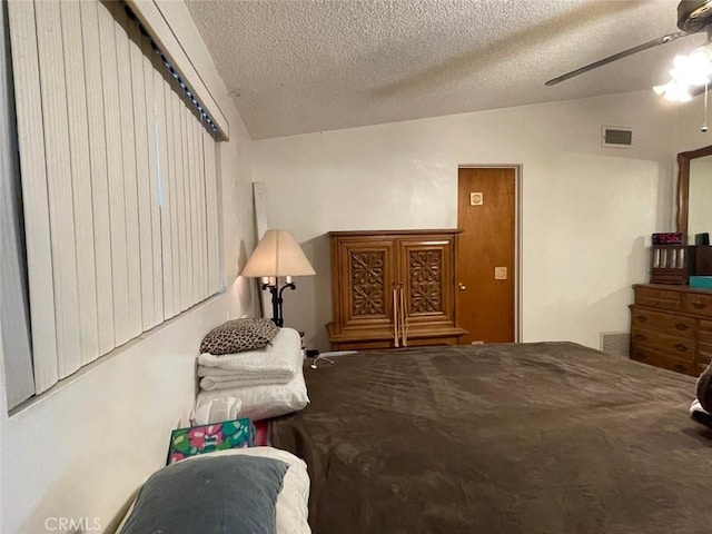 bedroom with ceiling fan, a textured ceiling, and vaulted ceiling