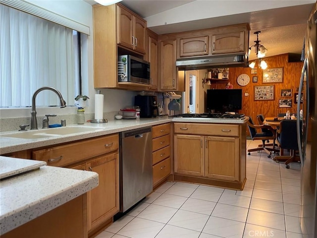 kitchen with wood walls, sink, light tile patterned floors, and stainless steel appliances