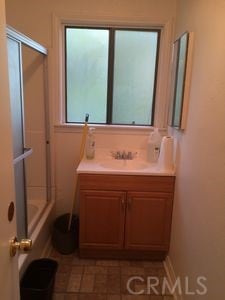 bathroom featuring tile patterned flooring, vanity, and bath / shower combo with glass door