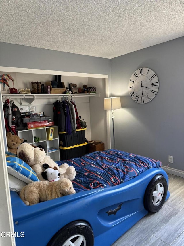 bedroom featuring a textured ceiling, a closet, and hardwood / wood-style flooring