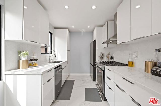 kitchen featuring sink, wall chimney range hood, tasteful backsplash, white cabinets, and appliances with stainless steel finishes