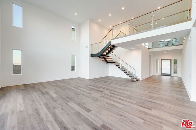 unfurnished living room featuring light hardwood / wood-style flooring and a towering ceiling