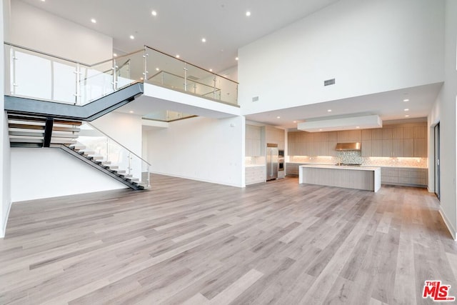 unfurnished living room with light hardwood / wood-style floors and a high ceiling