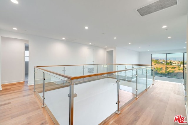 corridor featuring floor to ceiling windows and light hardwood / wood-style flooring