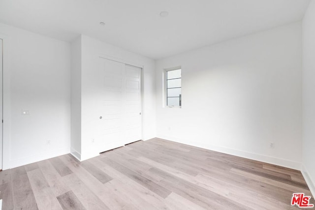 unfurnished bedroom with a closet and light hardwood / wood-style flooring