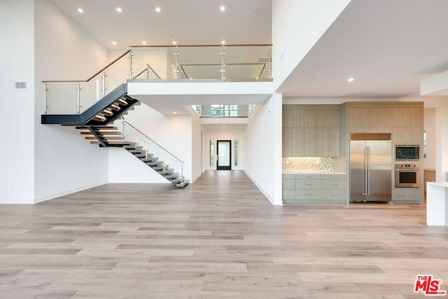 entryway with light wood-type flooring and a towering ceiling