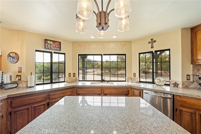 kitchen featuring backsplash, a wealth of natural light, hanging light fixtures, and stainless steel dishwasher