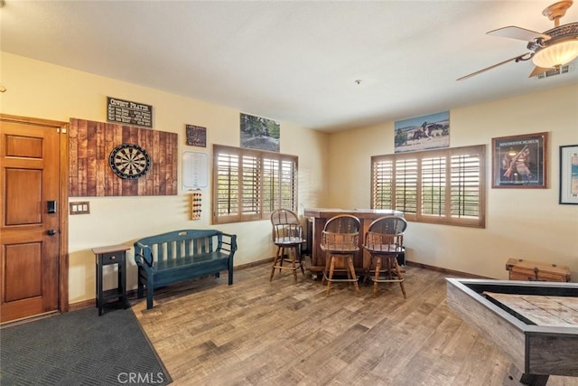 dining room featuring bar, ceiling fan, wood-type flooring, and a wealth of natural light